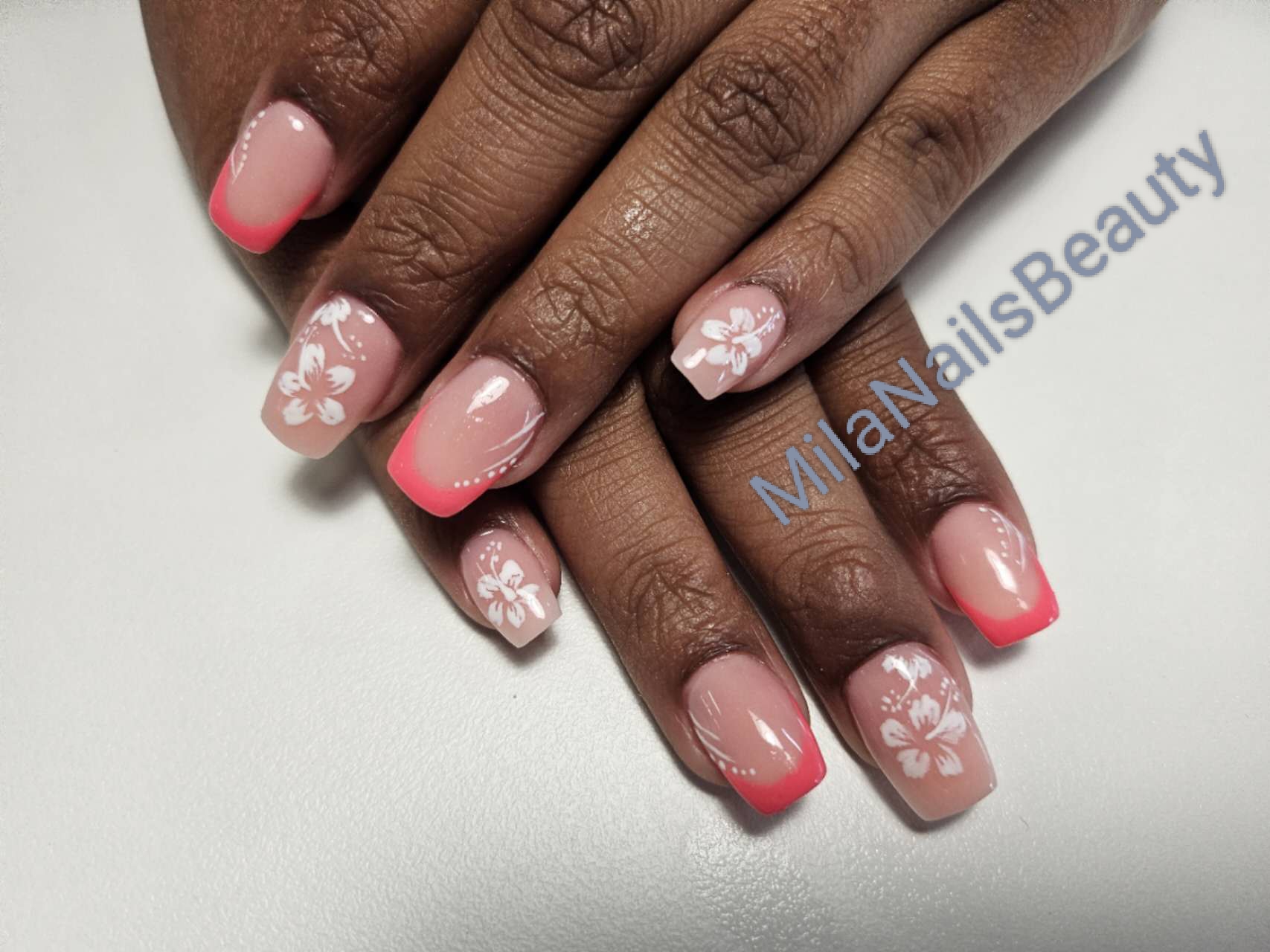 Korte vierkante nagels, nude met koraalrode tips en witte bloemetjes